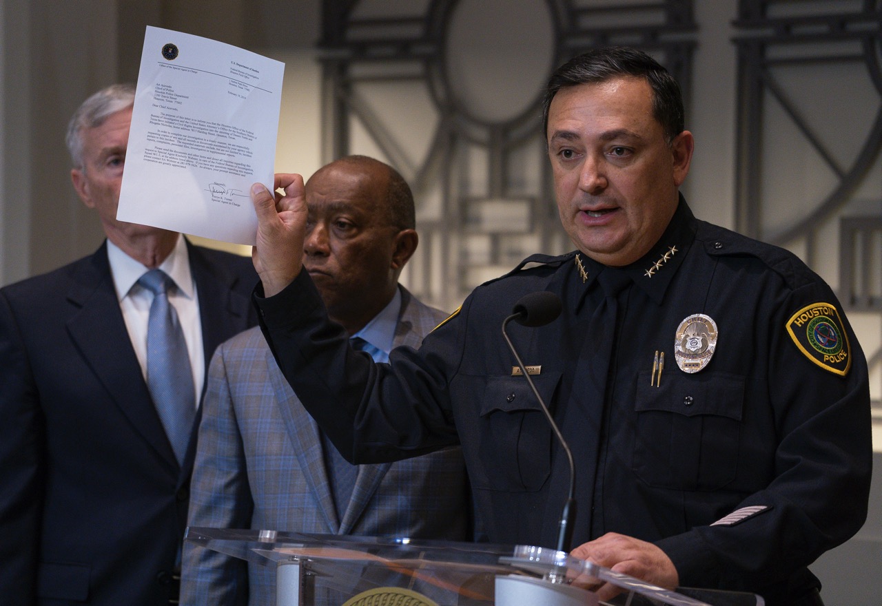 A police chief standing behind a podium holding a letter up