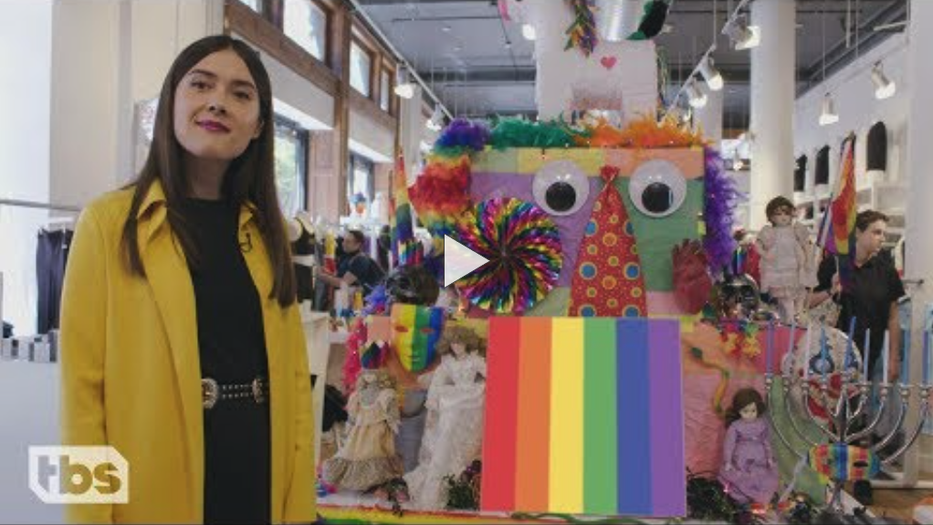 A woman with long, dark hair stands in a store, in front of a colorful display.