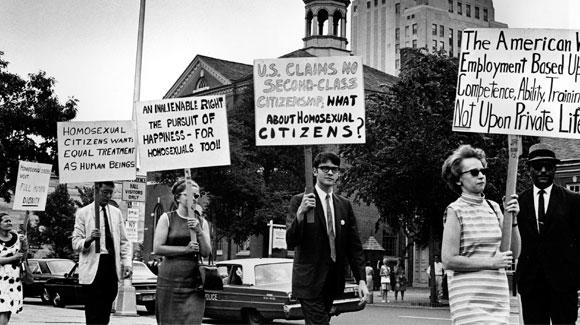 Demonstrators carry signs calling for protection of LGBTQ people from discrimination