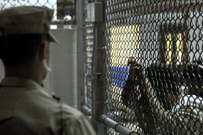 a prisoner is seen through a fence