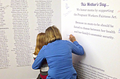 A mother and child sign the 'Largest Mother's Day Card Ever to Hit Capitol Hill'