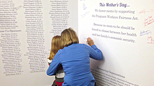 A mother and child sign the 'Largest Mother's Day Card Ever to Hit Capitol Hill'