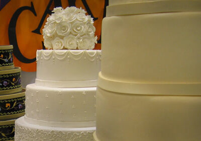 two 3-tier white wedding cakes, one with white flowers on top