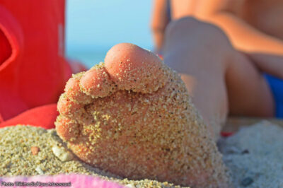 Kid's sandy foot on beach