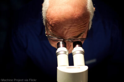 Photo of man peering into microscope