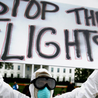 Protester holding "Stop the Flights!" sign