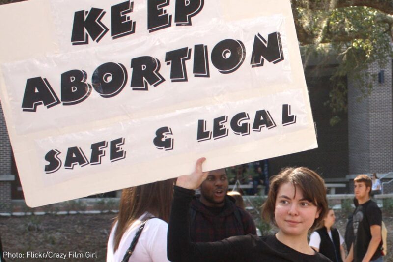 Girl holding "Keep Abortion Safe and Legal" sign