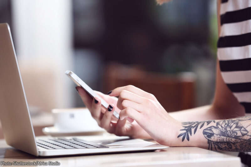 Woman using a mobile device and laptop