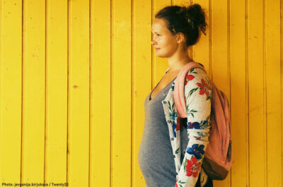 Pregnant woman in front of yellow background.