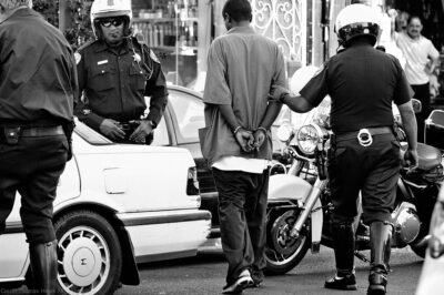 Police surrounding handcuffed man