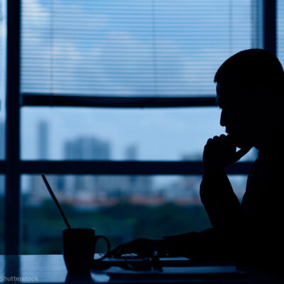 Silhouette of man looking at laptop