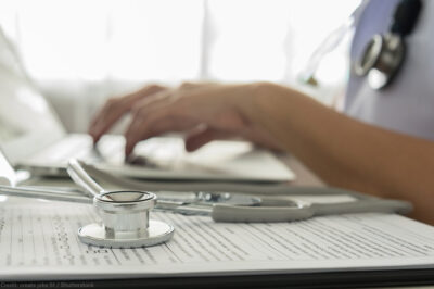 A doctor typing on a laptop computer