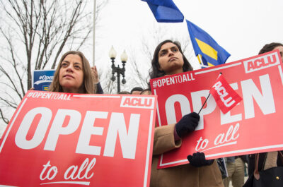 Demonstrators holding signs with the message 'Open to All"