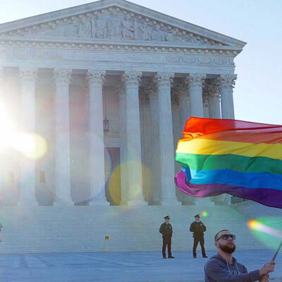 Man waving rainbow flag in front of Supreme Court