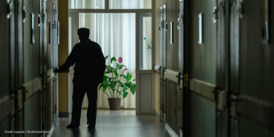 A resident walks down the darkened hall of a nursing home.