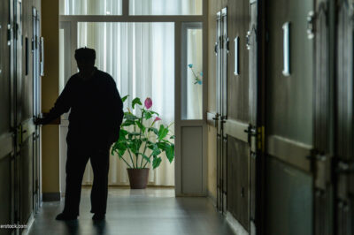 A resident walks down the darkened hall of a nursing home.