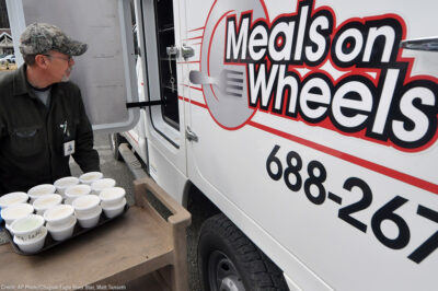 A Meals on Wheels driver loading food into a truck
