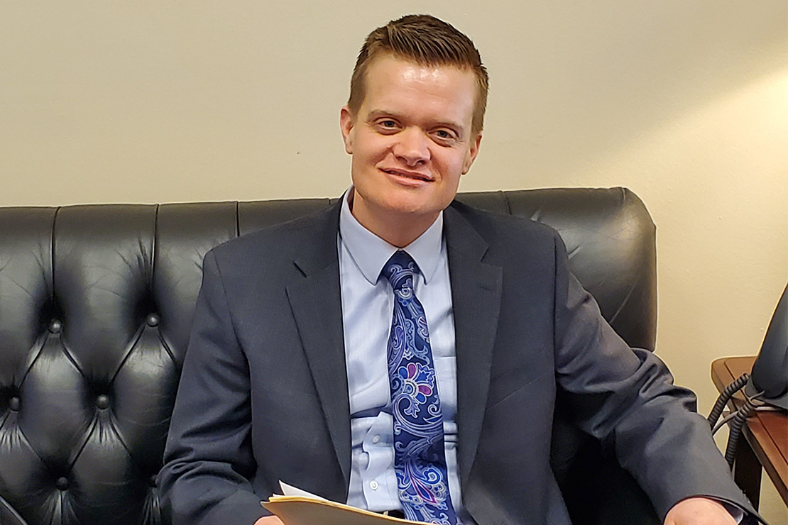 Photo of Evan Minton sitting on a couch in an office.