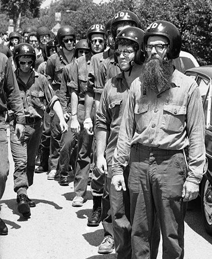 A black and white photo of a line of men wearing helmets