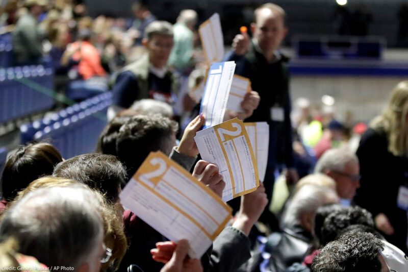 Caucus goers in Des Moines, Iowa hold up their first votes for their 2020 Democratic presidential candidate pick.