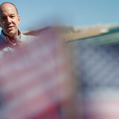 Anthony Romero speaks in the background while mini American flags wave blurred in the foreground.