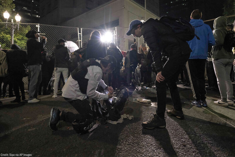 Two journalists prepare for police use of force.