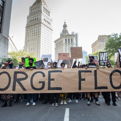 Black Lives Matter demonstrators marching with a large banner with George Floyd's name.