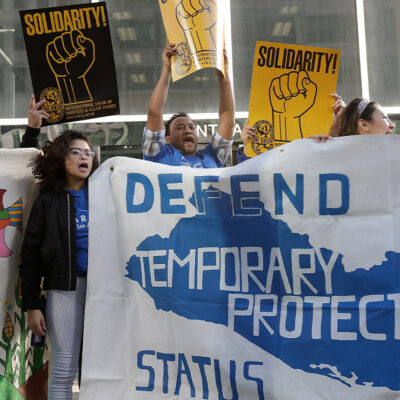 Supporters of temporary protected status immigrants hold signs and cheer at a rally in support of a program that lets immigrants live and work legally in the United States.