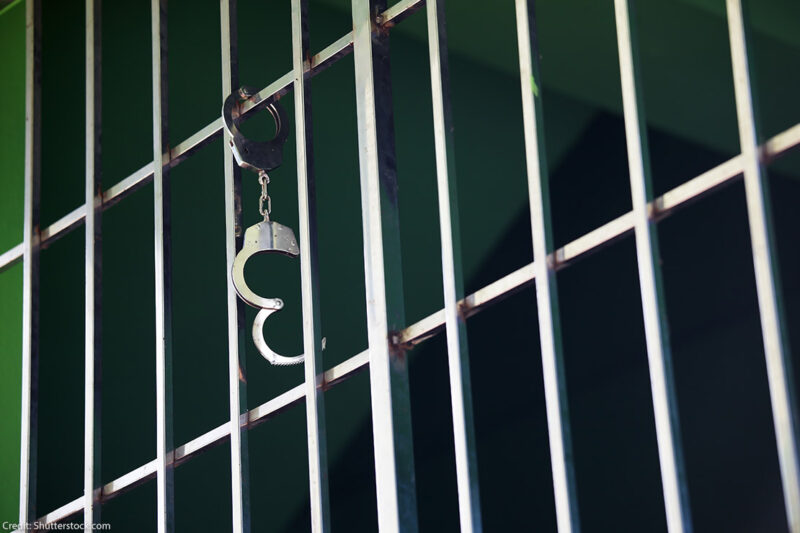 Handcuffs hanging from jail cell.