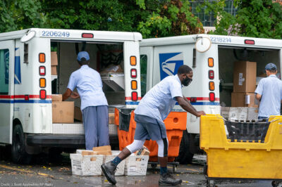 Letter carriers load mail trucks for deliveries at a U.S. Postal Service facility.