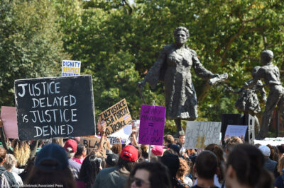 Marchers carry their signs into Lincoln Park with the Mary McLeod Bethune Memorial in the background.
