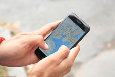 A man holding iPhone with navigation map app open on screen.