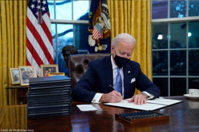 President Joe Biden signs his first executive order in the Oval Office of the White House.