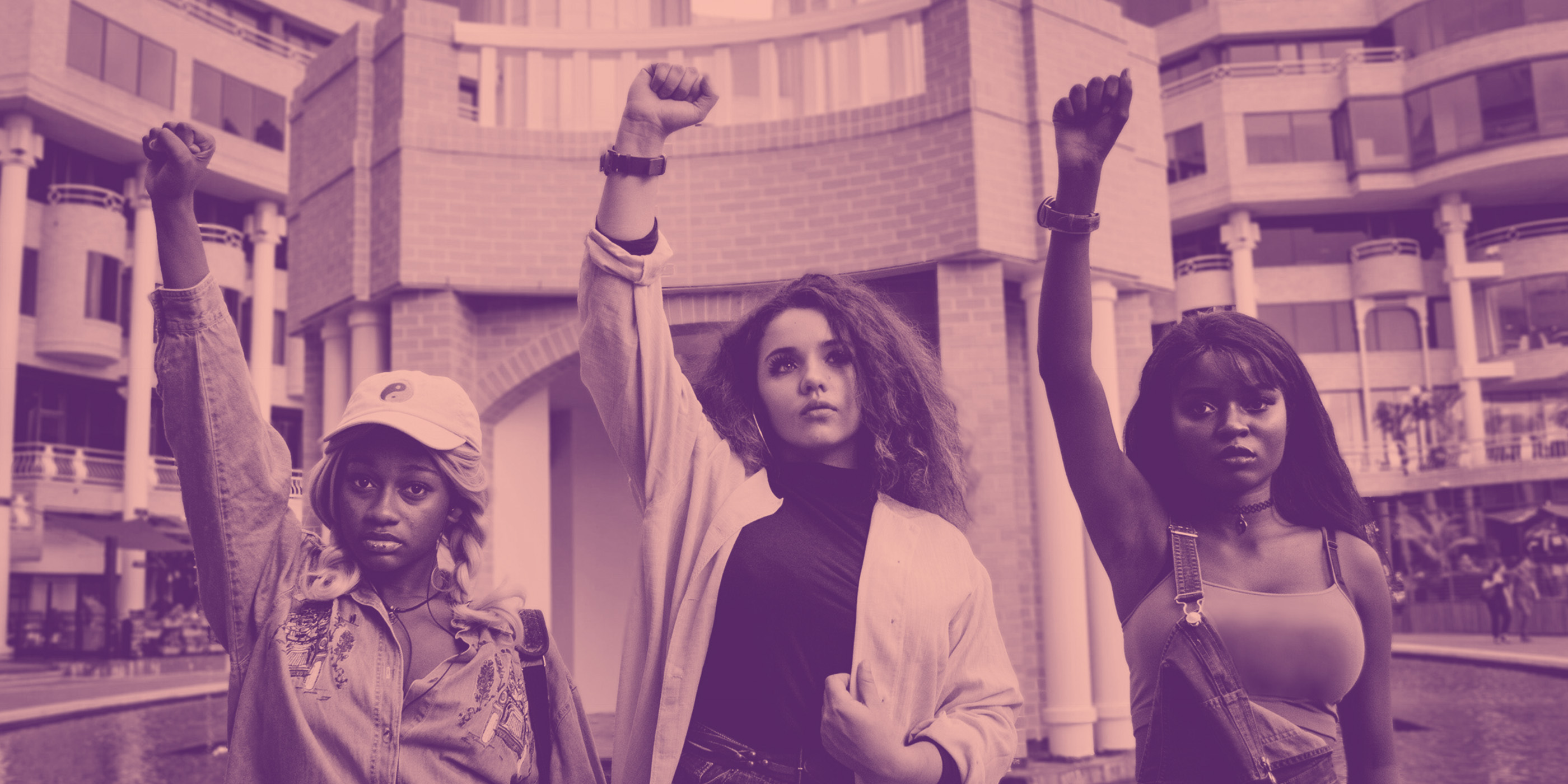 Girls in protest raising fists on pink background