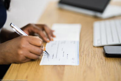 A black woman signs a cashier's cheque.