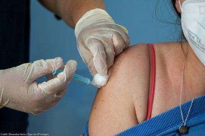 A Covid-19 vaccinator administers the Oxford/AstraZeneca vaccine to a woman at a vaccination centre in London