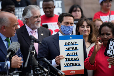 Rep. Trey Martinez Fischer, D-San Antonio, holds a sign that says, "Don't mess with Texas," as he and other Democratic caucus members join a rally on the steps of the Texas Capitol to support voting rights