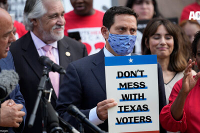 Rep. Trey Martinez Fischer, D-San Antonio, holds a sign that says, "Don't mess with Texas," as he and other Democratic caucus members join a rally on the steps of the Texas Capitol to support voting rights