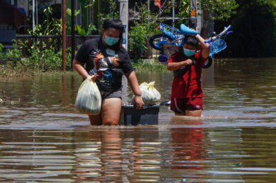 Residents carrying their belongings wade through floodwaters as Pasak Jolasid Dam overflows.