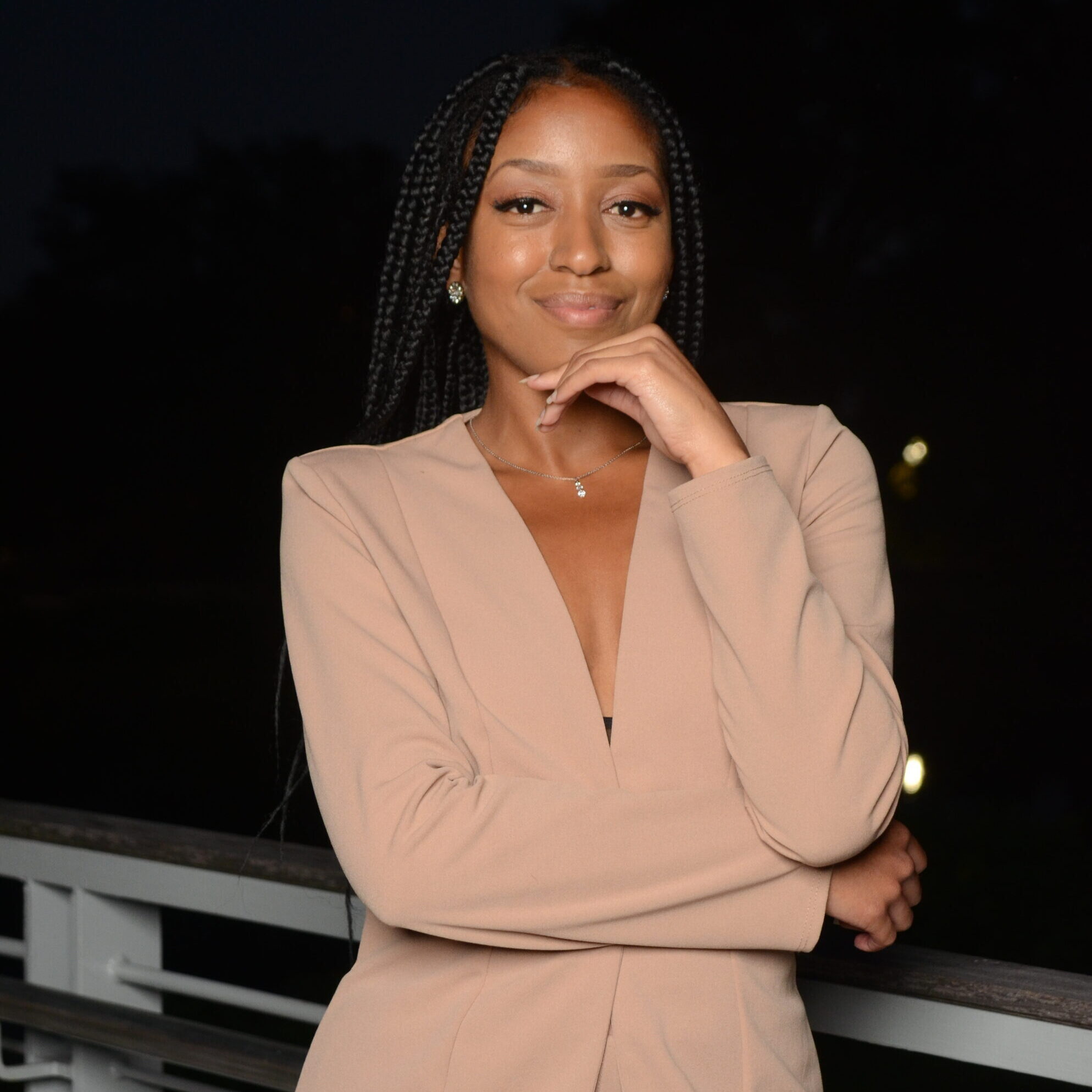 Headshot of Shamyra Lavigne in a tan suit against a dark sky because it's night time.