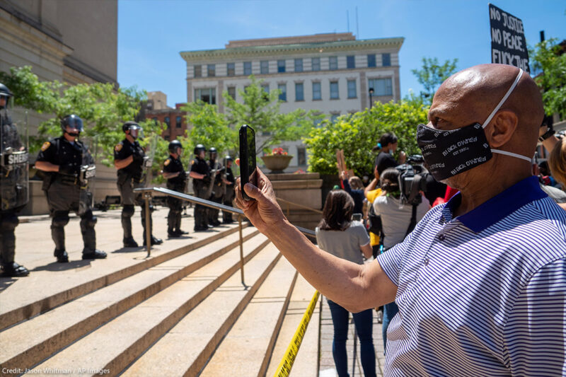 Man recording a line of police people