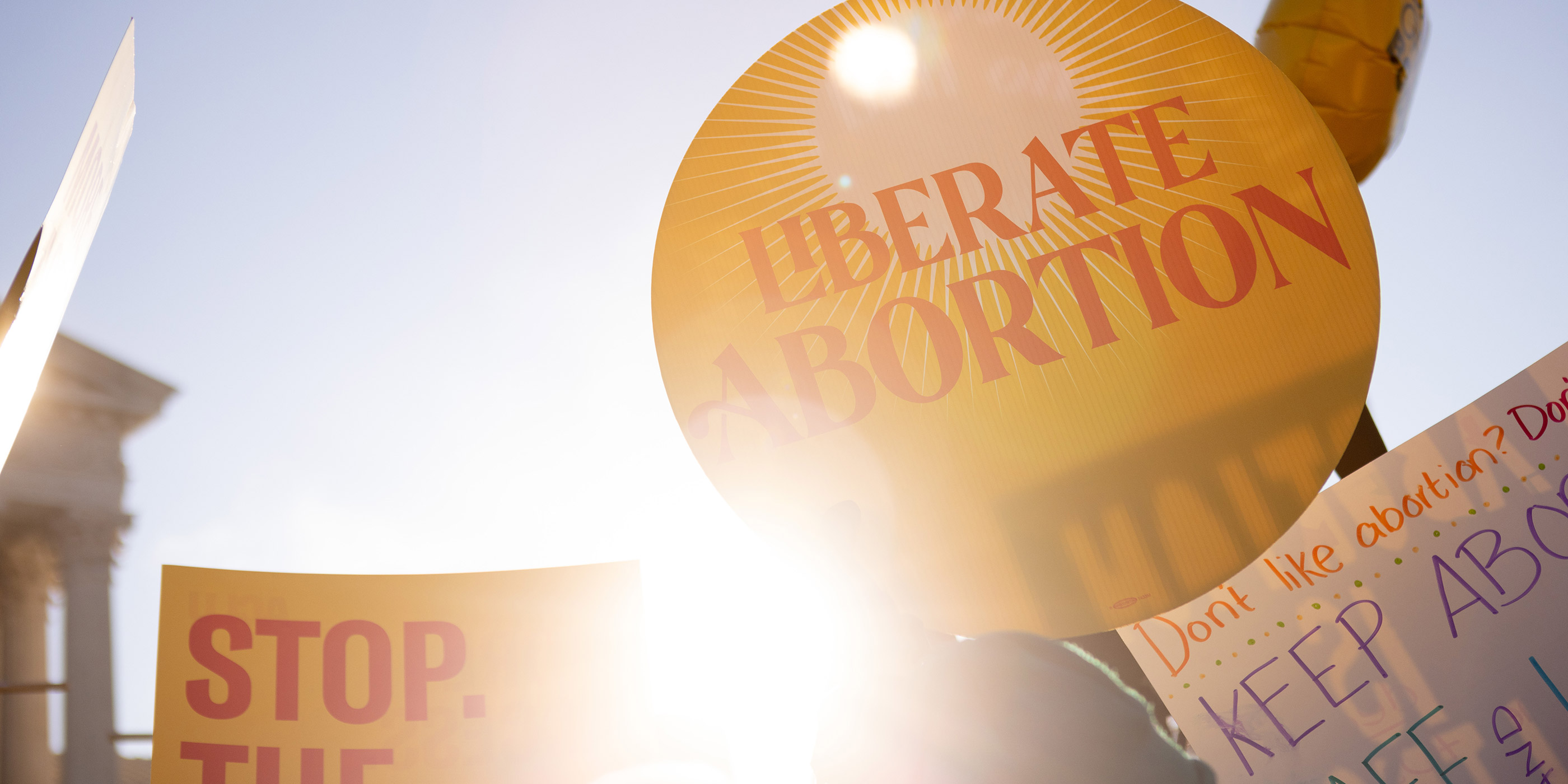 A group of signs, with one reading “Liberate Abortion.”