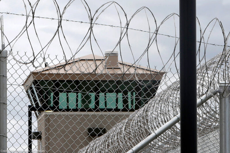 A guard tower over the fence at a correctional health care facility.