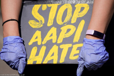 Woman holds a sign stating “Stop AAPI Hate.”