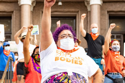 Activists wearing "Bans off our bodies" shirt and throwing fists in the air