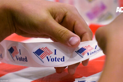 A volunteer prepares "I Voted" stickers at a polling station.