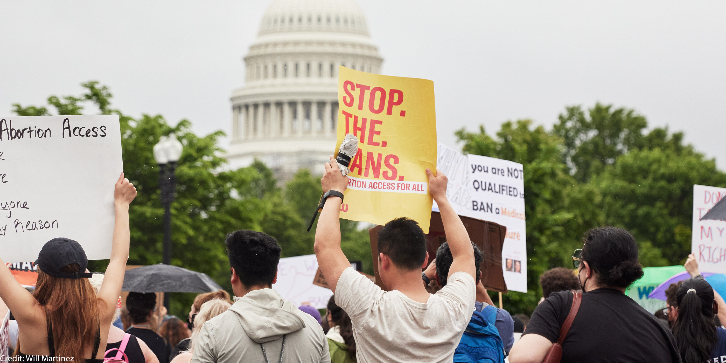 A group of people holding reproductive rights signs in front of the Capitol Building.