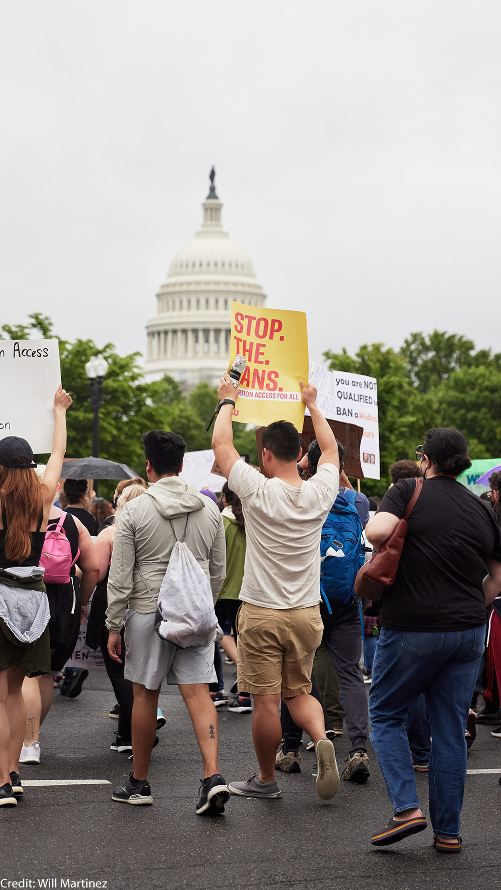 A group of people holding reproductive rights signs in front of the Capitol Building.