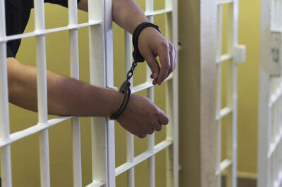 Handcuffed hands through prison bars