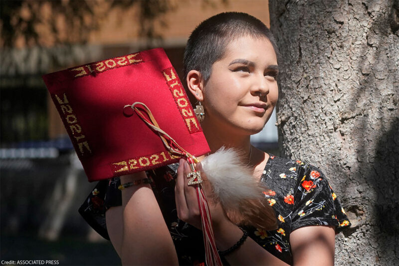 Emalyce Kee, holding up her "forbidden" graduation cap that she decorated with Native beads on May 25, 2022, in Cedar City, Utah.